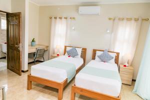 a bedroom with two beds and a desk at Jonc d'Or Villa Self Catering in La Digue