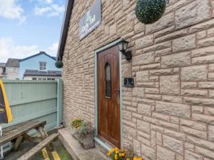 a brick building with a wooden door and a bench at Curly Tail Accommodation in Bishops Castle