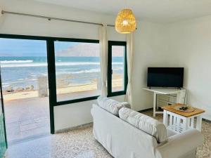 a living room with a white couch and a view of the beach at Famara Frontsea house in Famara
