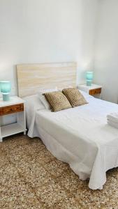a bedroom with a white bed with two night tables at Famara Frontsea house in Famara