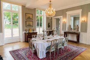 una sala da pranzo con tavolo, sedie e lampadario pendente di Château du Rondon a Olivet