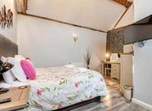 een slaapkamer met een bed met roze kussens en een bureau bij Curly Tail Accommodation in Bishops Castle