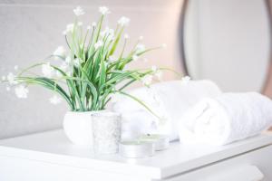 a white shelf with a vase of flowers and towels at Mysa Properties - Ampio monolocale in zona Bande Nere in Milan