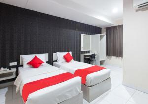 two beds in a hotel room with red pillows at Hotel Pulai Ipoh in Ipoh