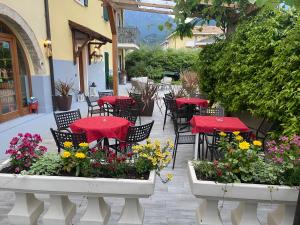 un patio extérieur avec des tables, des chaises et des fleurs dans l'établissement Agritur Girasole, à Arco