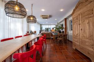 una sala da pranzo con un lungo tavolo e sedie rosse di Torre Lolita - House in Lleida for 8 with pool and tennis court a Lleida