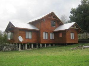 a large wooden house on a grassy field at Cabañas Los Canelos Pucon, Hermosa Granja de 20 hectaréas a orillas del Río Liucura in Pucón