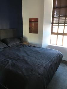 a bedroom with a bed with a blue comforter and a window at Prestwick Flat Central Location in Prestwick