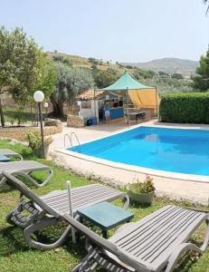 a swimming pool with two lawn chairs and a table at Agriturismo Giannavi in Palazzolo Acreide