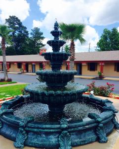 a fountain in front of a building with palm trees at Deluxe Inn - Savannah in Savannah