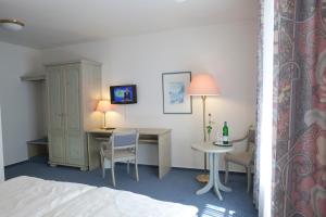a hotel room with a bed and a desk and a table at Landhaus Sterdebüll in Bordelum