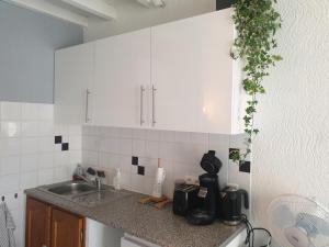 una cocina con armarios blancos y fregadero en Studio tout confort centre ville - Balcon, Clim, TV, Wifi, en Mazan