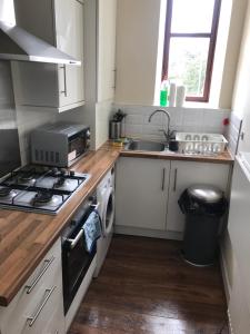 a kitchen with a stove top oven next to a sink at Prestwick Flat Central Location in Prestwick