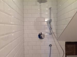 a white tiled shower with a blow dryer at Seafront, 2 bed apartment in quiet central area in Pembroke