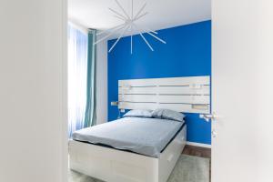 a blue bedroom with a white bed and a blue wall at Botique Apartment • Trieste City Center [Wifi] in Trieste