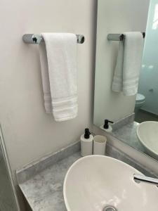 a bathroom with a sink and a mirror and towels at Depa enfrente del Hotel RIU @serra in Guadalajara