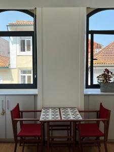 a table and chairs in a room with two windows at Smart Living in Aveiro