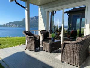 um alpendre com cadeiras de vime e uma mesa com vista em Nice little house right by the sea, stunning view! em Renså