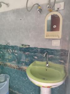a bathroom with a green sink and a mirror at Aditya guest House and restaurant in Trijugi Nārāyan