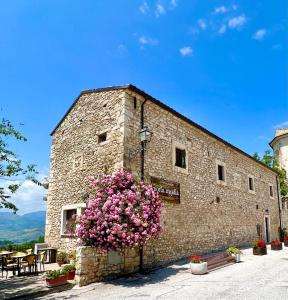 a stone building with pink flowers in front of it at Affittacamere Porta Majella in San Valentino in Abruzzo Citeriore