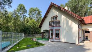 ein weißes Haus mit einem Zaun neben einem Hof in der Unterkunft Dom Na Skraju Mazur in Olsztyn
