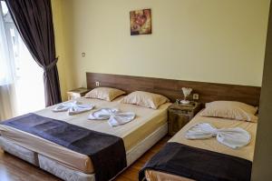two beds in a hotel room with towels on them at Edelvais Guest House in Primorsko