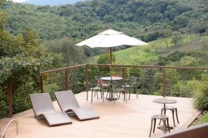un patio con mesa, sillas y sombrilla en Villa Severina, en Brumadinho