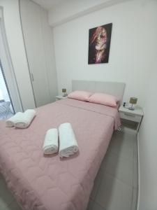 1 dormitorio con 1 cama rosa y 2 toallas en Stojanović apartman Jagodina, en Jagodina