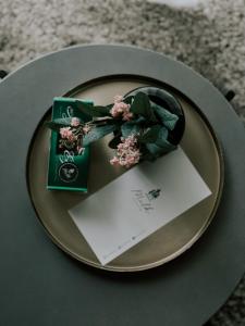 um prato com um cartão e flores sobre uma mesa em Camping Milk em Usmenieki