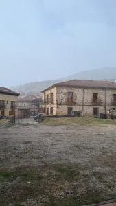 an old stone building with a field in front of it at Apartamentos Casa de los Ramos in Vinuesa