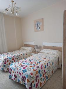 a bedroom with two beds with a floral bedspread at Albergue Agarimo in Caldas de Reis