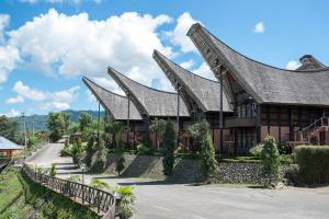 a house with a gambrel roof on a street at Toraja Heritage Hotel in Rantepao