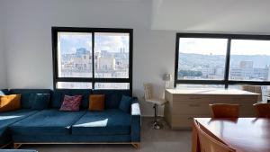 a blue couch in a living room with windows at Unique Penthouse in Center of Haifa in Haifa