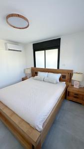a bedroom with a large white bed with a large window at Unique Penthouse in Center of Haifa in Haifa