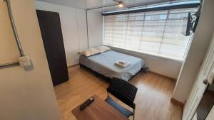 um pequeno quarto com uma cama e uma janela em Apartaestudios Amoblados Galerías em Bogotá