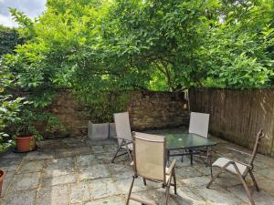 a patio with a table and chairs under a tree at The Coach House in Hawkhurst