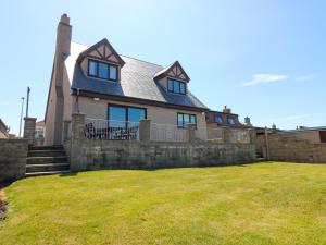 a house with a stone retaining wall and a yard at Shoreline House in Fraserburgh