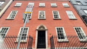 ein rotes Backsteingebäude mit einer schwarzen Tür und Fenstern in der Unterkunft Merrion Square Studios in Dublin