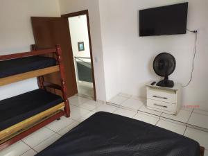 a bedroom with bunk beds and a flat screen tv at CASA DE TEMPORADA in Peruíbe