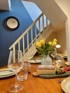 a table with wine glasses and a vase with yellow flowers at Stylish 2-bedroom Townhouse next to Brighton Station in Brighton & Hove