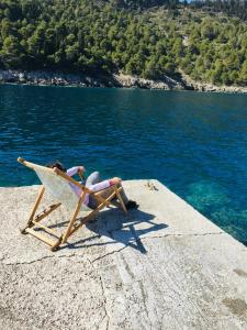 eine Person, die auf einem Stuhl am Strand in der Nähe des Wassers liegt in der Unterkunft The Cove Assos in Asos