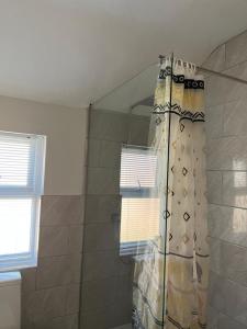 a shower curtain in a bathroom next to a window at Newton Road Home A small cosy comfortable 2 bedroom terrace house in Great Meols