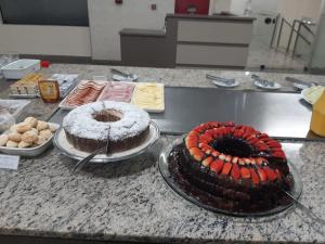 a counter with two cakes on plates on it at Astron Suítes São José dos Pinhais by Nobile in São José dos Pinhais