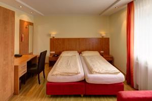 1 Schlafzimmer mit 2 Betten, einem Schreibtisch und einem Schreibtisch in der Unterkunft Gästehaus Leimer Bräu in Lenzing