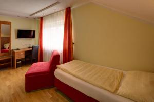 ein Schlafzimmer mit einem Bett, einem Stuhl und einem Schreibtisch in der Unterkunft Gästehaus Leimer Bräu in Lenzing