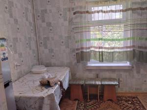 a room with a bed and a window and a table at Karakol apartment in Karakol