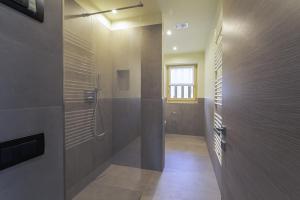 uma casa de banho com um chuveiro e uma porta de vidro em Arion Apartments - Trepalle em Livigno
