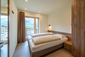 um quarto com uma cama e uma grande janela em Arion Apartments - Trepalle em Livigno