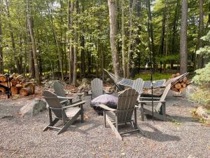 a group of chairs and a hammock in the woods at Stylish and Cozy Cabin, Walking Distance to Big Bass Lake in Gouldsboro