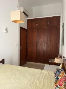 1 dormitorio con 1 cama grande y armario de madera en Vilamoura Alecrim, en Vilamoura